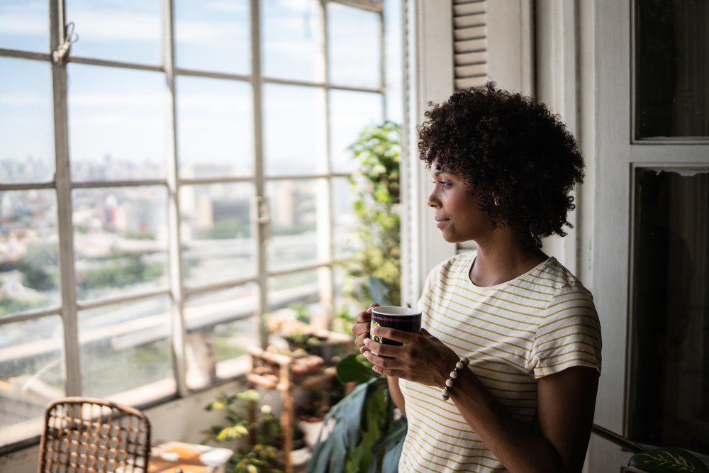 Homeowner enjoying natural light near a large residential window